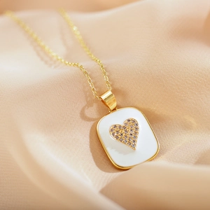 Elegant gold necklace with white enamel pendant and heart-shaped zircon on silk fabric