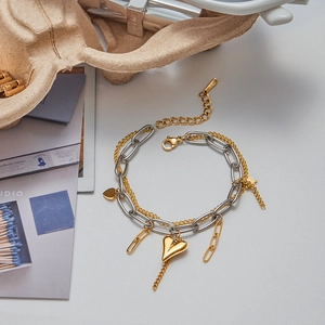 Detail of two-tone stainless steel layered bracelet with gold heart and star charms