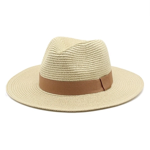 Close-up of woven straw texture and brown decorative ribbon on beige Panama hat