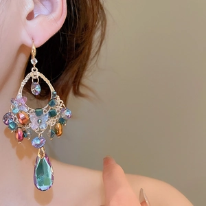 Detail of bohemian drop earring with colorful crystals and teardrop pendant on ear