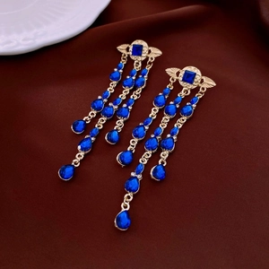Detail of vintage gold tassel earrings with deep blue gemstones and crystal accents