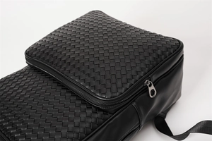 Close-up of black woven leather texture and metal zipper detail on the backpack