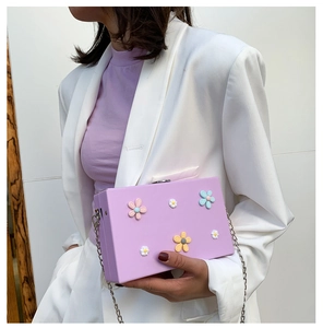 Detailed close-up of a purple box bag with colorful floral 3D decorations and metal chain