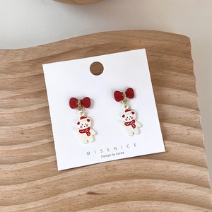 Close-up of Christmas teddy bear stud earrings with red bow on a wooden display