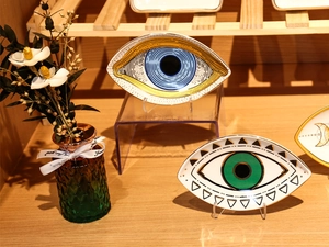 Detailed close-up of ceramic evil eye jewelry trays in blue and green on a wooden stand