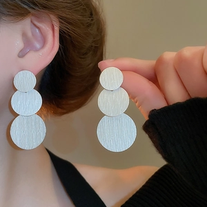 Macro shot of silver brushed metal triple circle earrings showing detailed texture