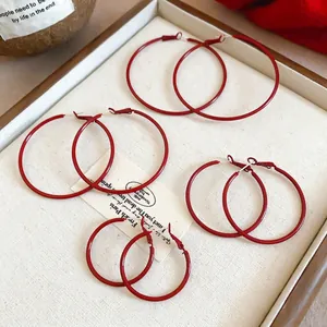 Minimalist matte red hoop earring set in four varied sizes on a beige display tray