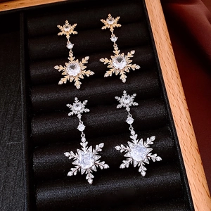 Close-up of 18k gold and silver snowflake dangle earrings with sparkling crystals