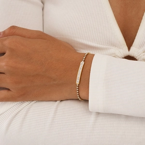 Close-up of a gold-plated bracelet featuring a sleek rectangular sparkling pavé diamond bar
