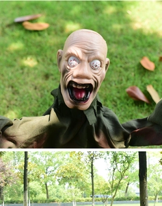 Macro shot of Halloween zombie ground breaker with bloodshot eyes and ragged green clothes