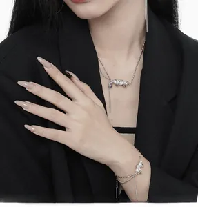 Detailed close-up of a minimalist pearl necklace and bracelet set on a black blazer