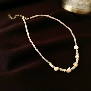 Détail de perles de nacre et perles dorées translucides sur fond de velours brun