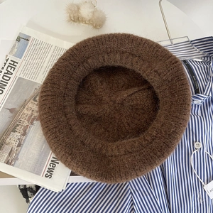 Detailed texture of brown mohair knit beret with stylish accessories and newsprint