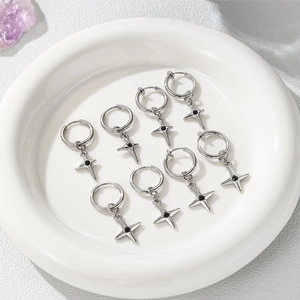 Flat lay of star-shaped silver steel earrings with black stone centers in white dish