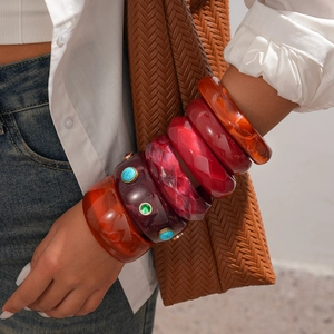 Detailed view of layered resin bangles in amber and red tones on a model's wrist
