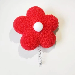 Macro view of red teddy velvet five-petal flower with a white plush center on a metal spring
