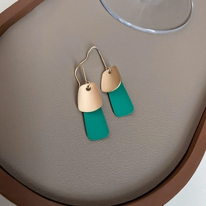 Macro detail of geometric earrings with matte gold and vintage green accents