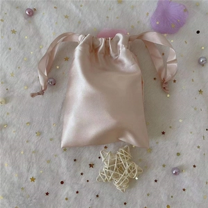 Macro detail of a pink satin drawstring storage bag with silky smooth texture