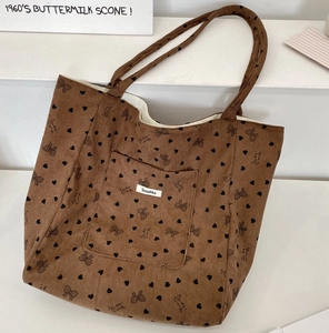 Detailed shot of coffee brown corduroy tote bag with black heart and bow pattern