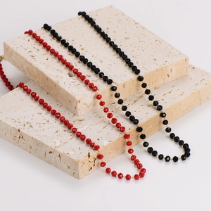Minimalist red and black beaded necklaces with faceted crystals on stone pedestals