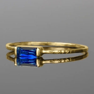 Gold ring with rectangle blue sapphire and hand-hammered texture on high-gloss surface