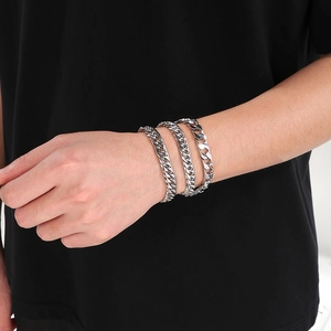 Polished silver stainless steel Cuban link bracelets in three sizes on a male wrist