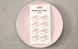 Close-up of 8pcs rose gold novelty paper clips in heart envelope shape on a card