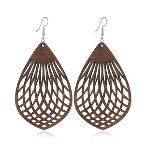 Détail de boucles d'oreilles en bois marron en forme de goutte avec motif grillagé ajouré