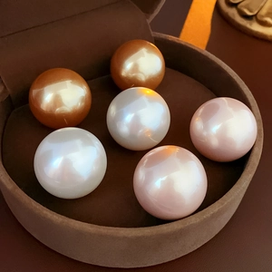 Macro detail of luxury vintage round pearls in gold, pink, and white on brown velvet