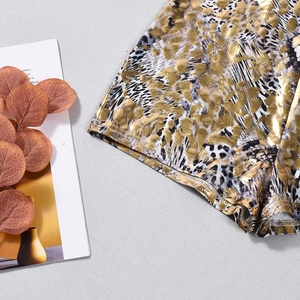 Detailed view of leopard print metallic jumpsuit fabric with shiny gold and black texture