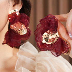 Detail of burgundy chiffon flower earring with gold metallic center and tulle texture