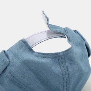 Détail de l'attache velcro réglable sur le bonnet en denim bleu clair sans bord