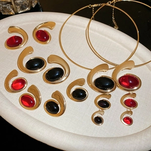 Detail of luxury gold metal necklace and earring set with red and black resin stones