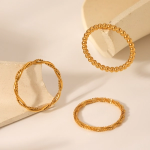 Detailed view of three gold braided rings displayed on minimalist geometric stone props