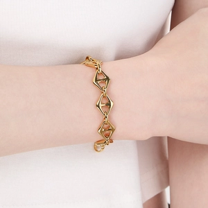 Poliertes goldenes Edelstahlarmband mit geometrischen Gliedern am Handgelenk im Minimal-Stil