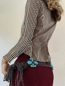 Detail view of brown plaid long sleeve shirt with turquoise beaded braided tassel belt