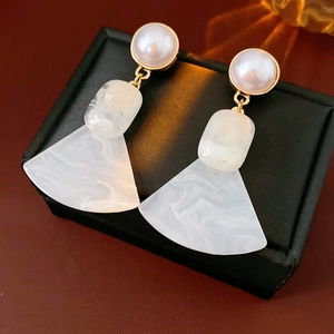Close-up of geometric pearl earrings with marble texture fan-shaped drop in gold