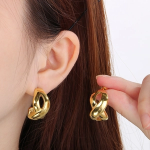 Close-up of elegant 18k gold plated infinity twist hoop earrings worn on a model