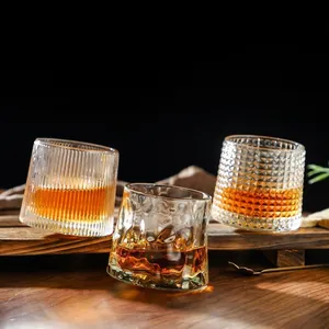 Rotating whiskey glass set with vertical, hammer, and grid textures on a wooden tray