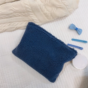 Close-up of navy blue faux shearling makeup bag with a durable metal zipper