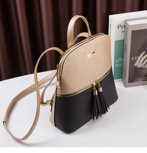 Detail of champagne and black dual-tone fashion backpack with textured finish and tassel