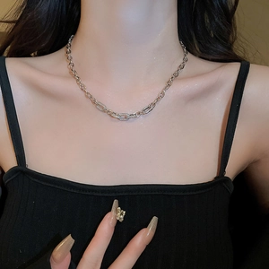 Macro view of a metallic chain necklace with geometric square links worn by a model