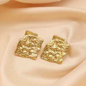 Macro detail of gold-plated earrings with unique hammered texture and layered design