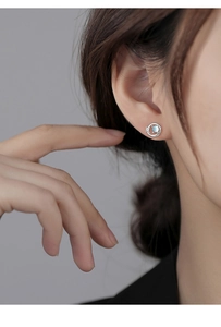 Close-up of minimalist silver Saturn earring with light blue stone and diamond accent