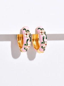 Macro shot of pink enamel C-shaped floral earrings with delicate white flower details