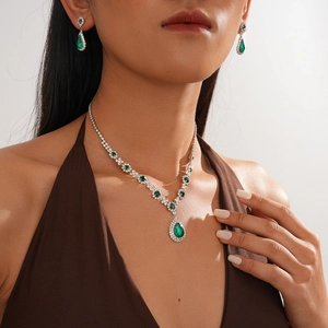 Detail shot of vintage jewelry set with green teardrop emerald pendants and silver plating