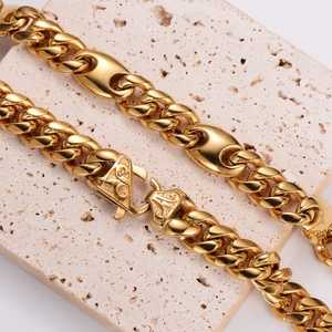 Polished gold Cuban chain necklace with a unique triangular clasp on a stone base