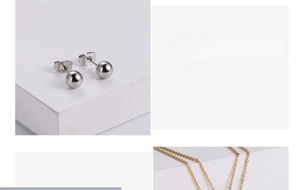 Parure de boucles d'oreilles boules argentées et chaîne dorée sur un support blanc