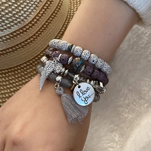 Detail of layered bohemian bead bracelet with silver wing charm and grey tassel