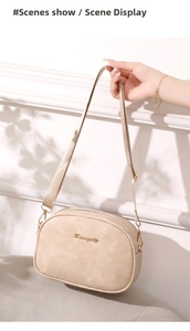 Detail view of beige oiled leather camera bag with golden logo and fabric strap